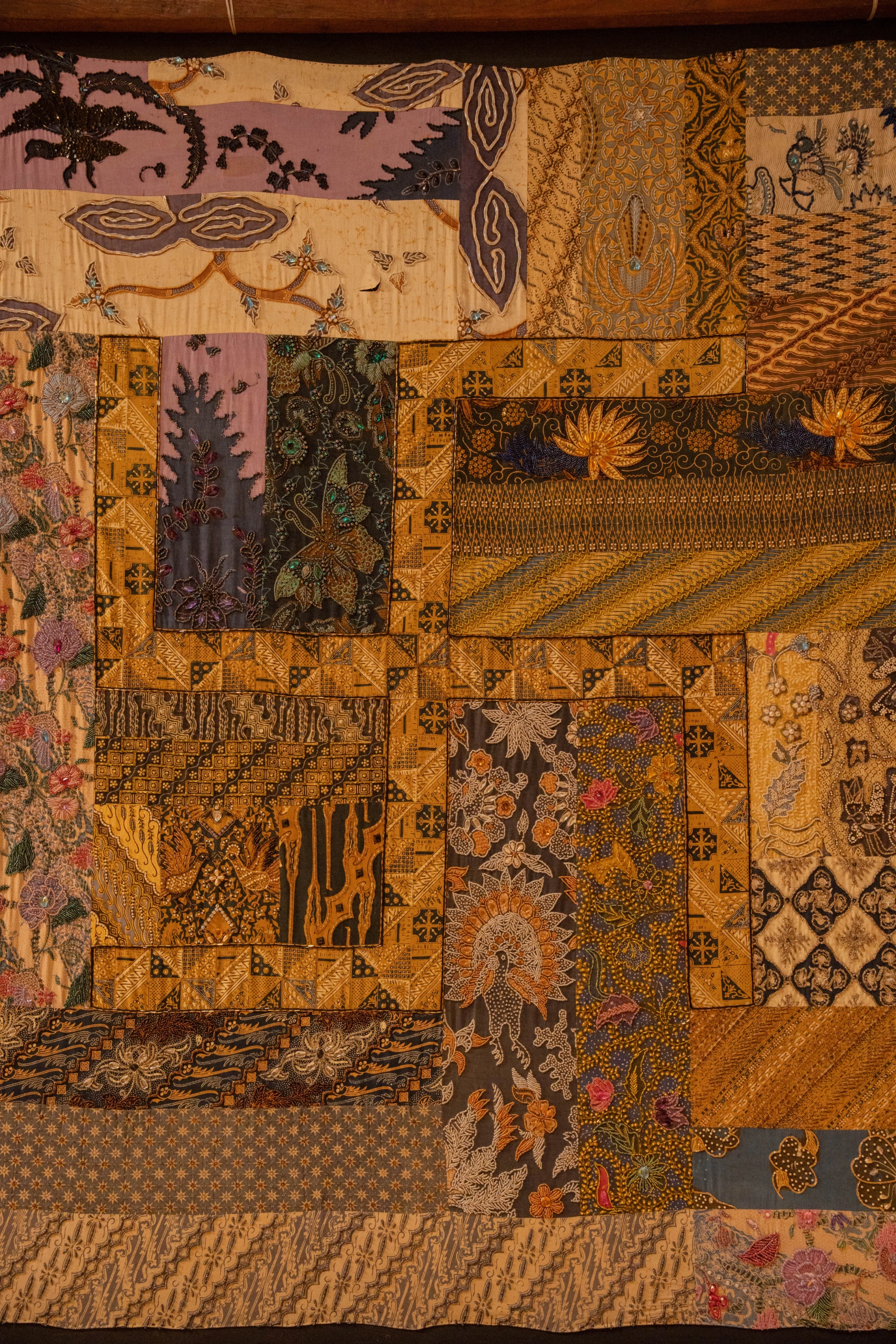 Close-up of ornate Balinese wood carvings and vibrant traditional textiles, Museum Peter Bloch Collection.