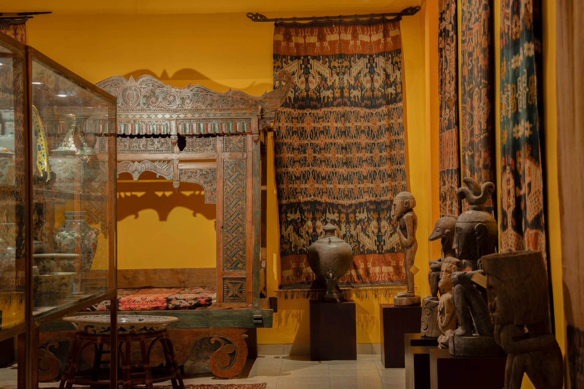 Textiles of traditional Balinese ceremonial ikat clothing against a vibrant red wall in the Ikat Room.