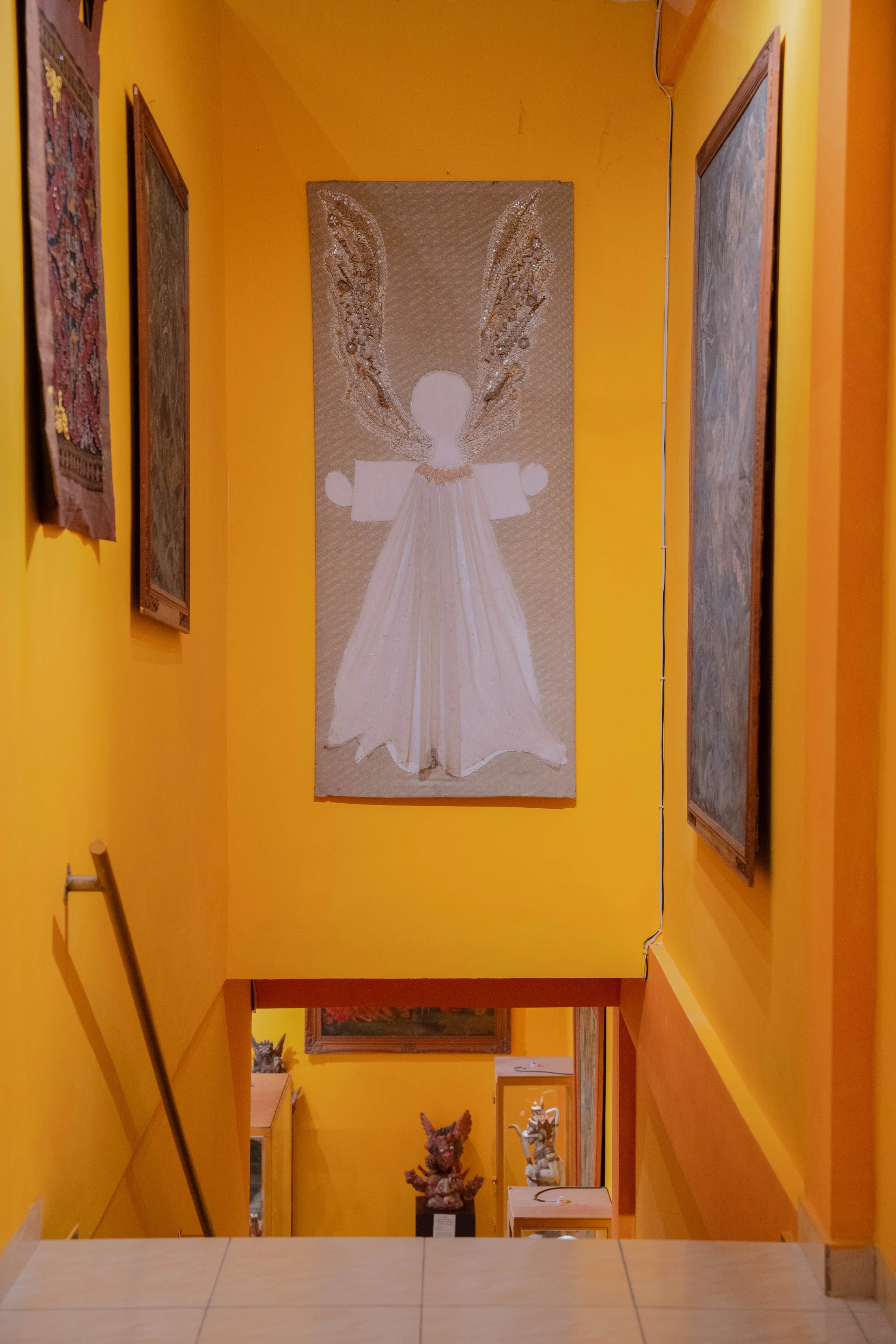 Framed archival portrait displayed alongside Balinese wood carvings and traditional fabrics.