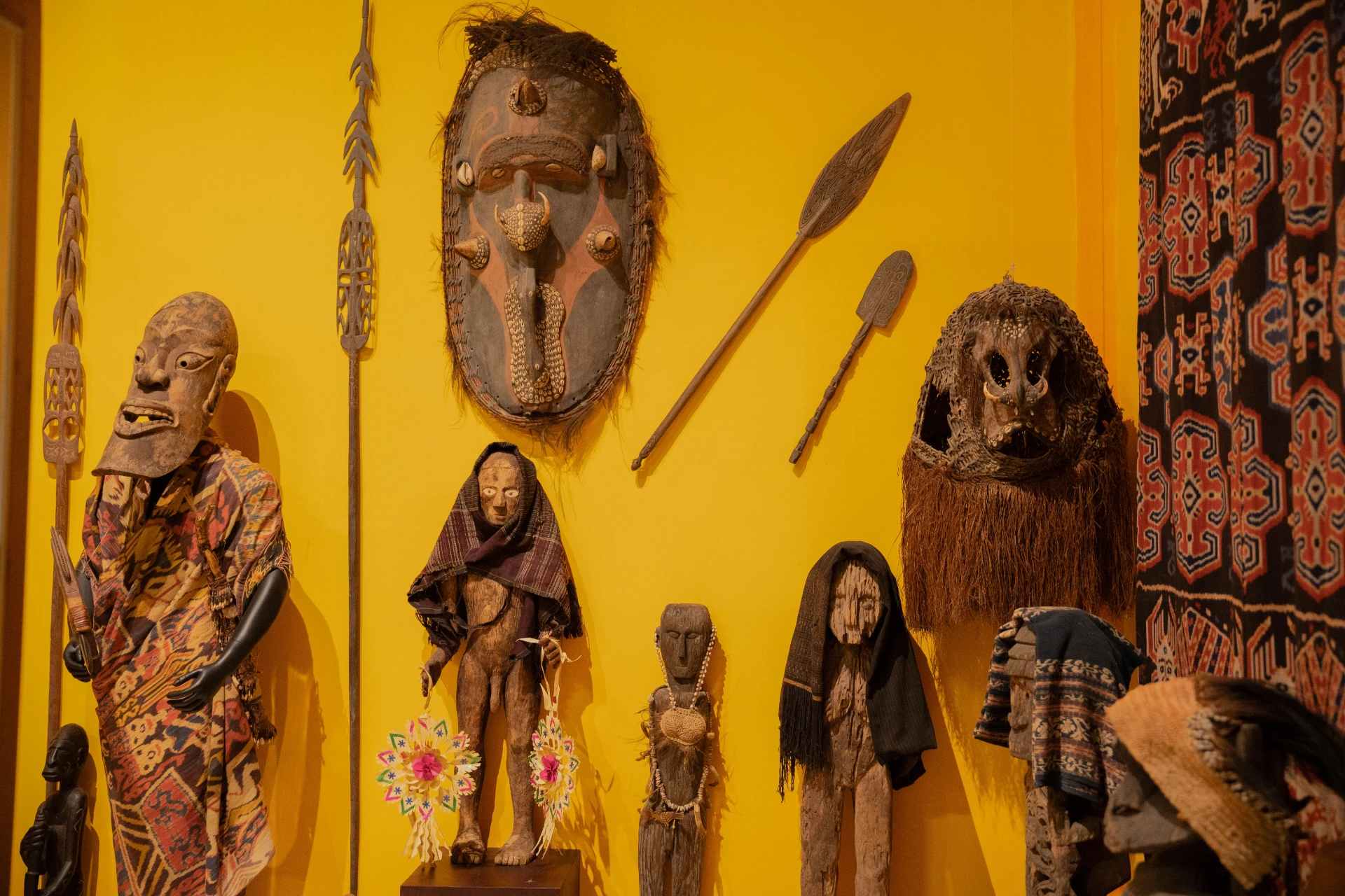 Traditional masks and sacred textiles curated within the glass displays of the Scary Room gallery.