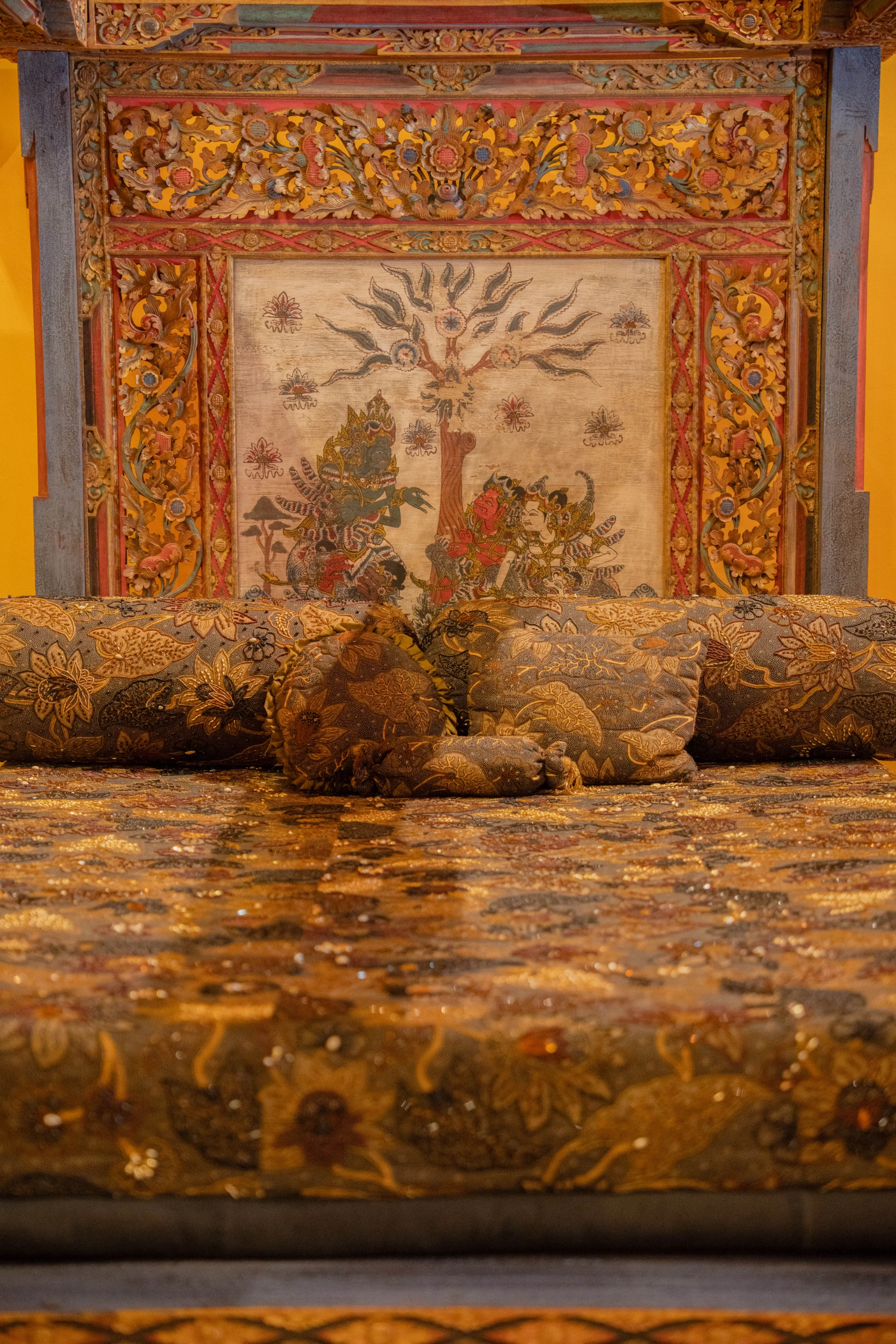 Close-up of ornate Balinese wood carvings and vibrant traditional textiles, Museum Peter Bloch Collection.